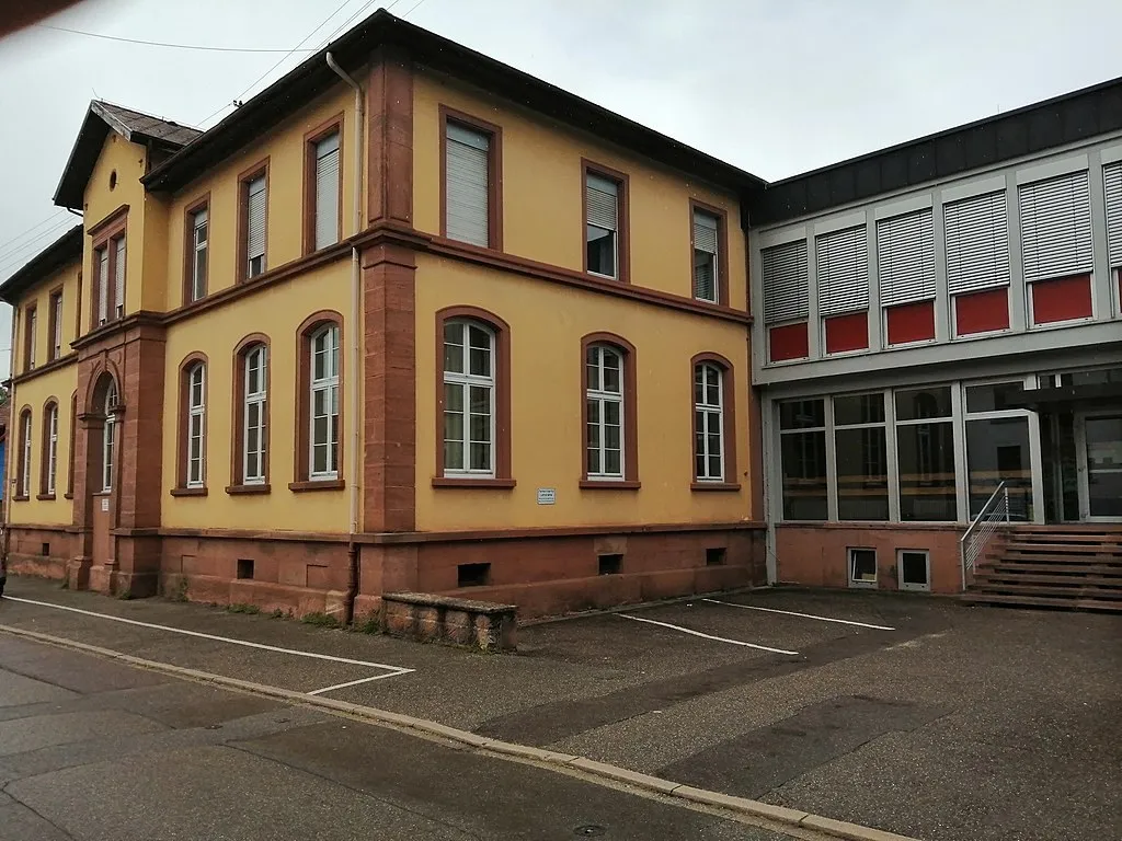 Der Altbau der Grundschule Sulz: gelbe Fassade mit rotem Sandstein, rechts daneben der Trakt mit großen Fenstern.