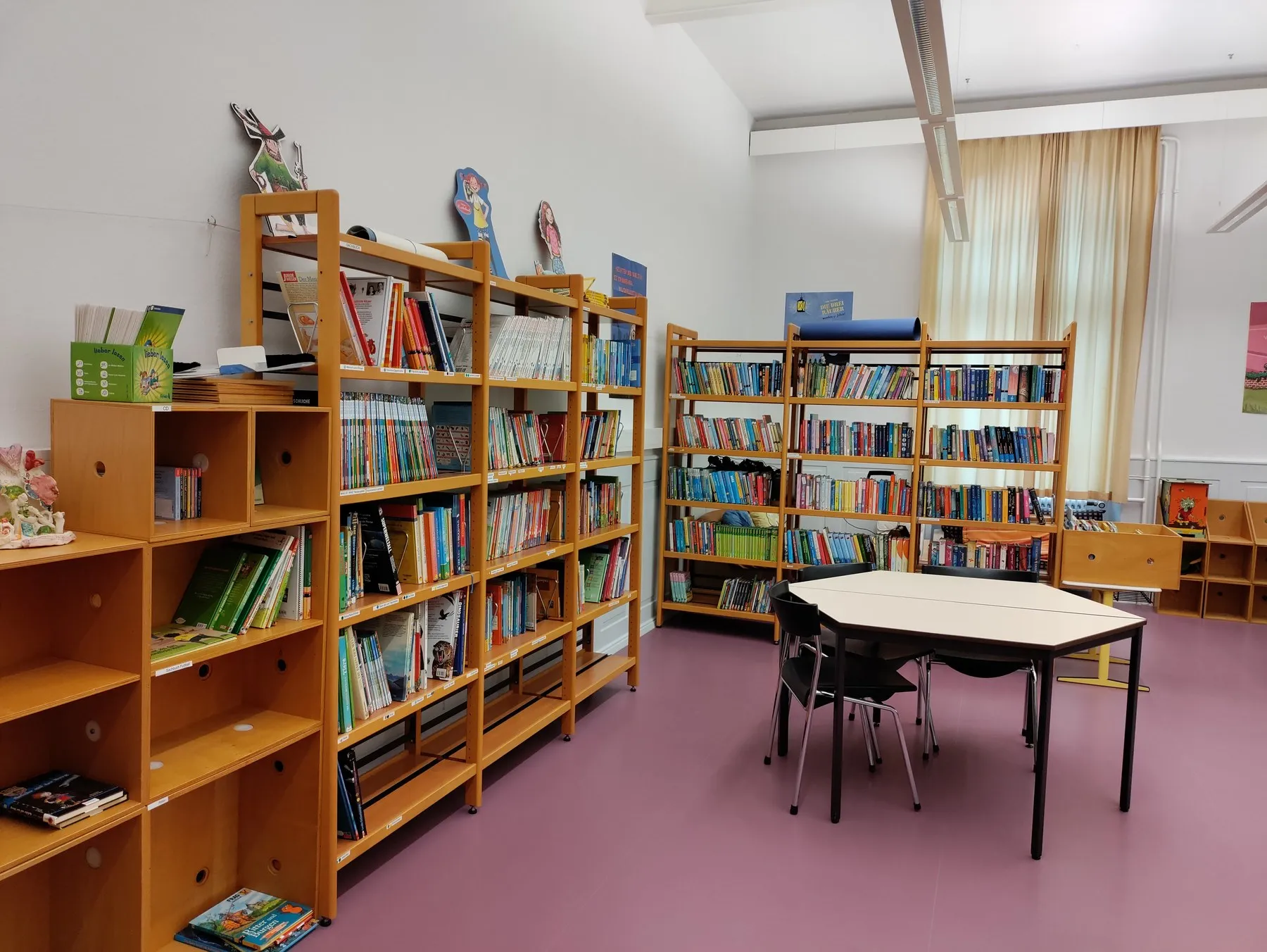 Die Schülerbücherei der Grundschule Sulz: helle Holzregale voller Kinderbücher, davor ein Gruppentisch mit Stühlen.